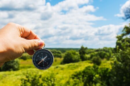 compass in hand close-up on the background of the summer landscape