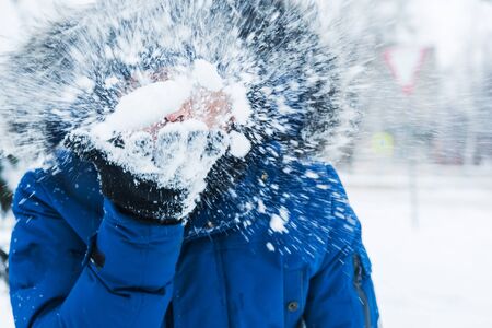 man holding snow in his hands and blowing on itの写真素材