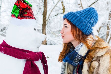 young beautiful woman playing with snowmanの写真素材