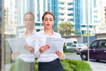 business woman reading a newspaper outdoors in the cityの写真素材