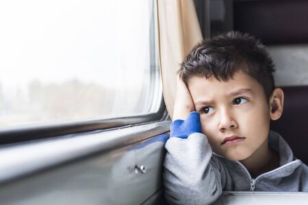boy 5 years goes to in a train and with sadness looks in window
