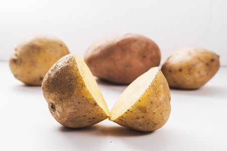 whole and cut potatoes on a white backgroundの写真素材