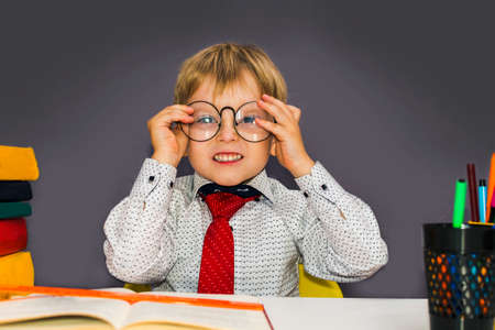 cute boy with glasses sitting at a Desk. Blond nerd with glasses.の写真素材