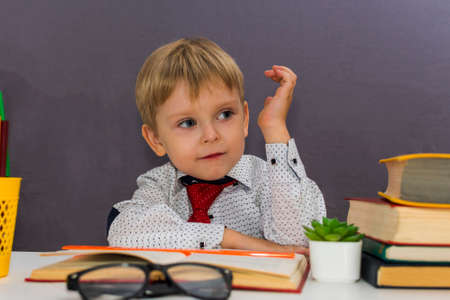 boy stretches out his hand. a preschooler sits at a Desk