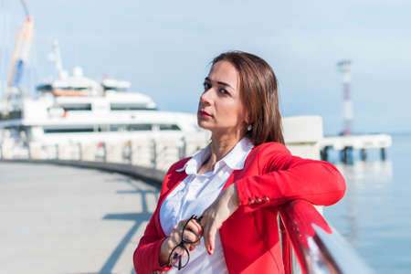 business woman in a red suit stands by the sea