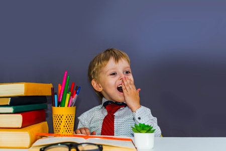 cheerful preschool boy at the table with booksの写真素材