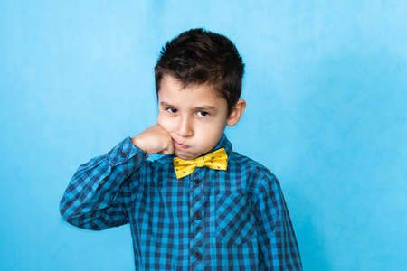 portrait of a little boy on a blue background. Boy showing fight gesture
