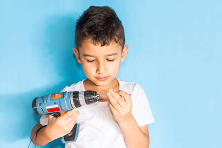 little boy learns to work with a screwdriver. Craftsmanship lessons with toolsの写真素材
