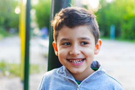 a cheerful little boy is playing in the yard near the house.