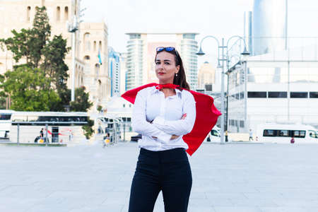 business successful woman with a superhero cape on the background of the cityの写真素材