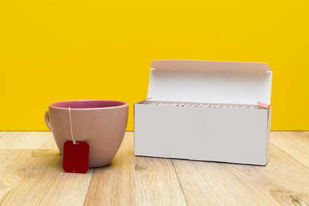 mug and packaging of tea bags on a yellow background