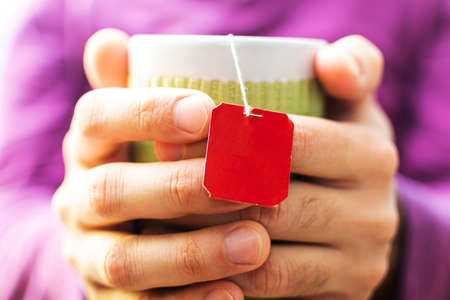 male hands hold a green mug close-up. packaged tea.の写真素材