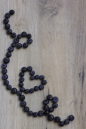 Blueberry heart decoration on a rustic wooden surface.の写真素材