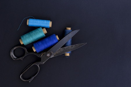 Sewing items. Scissors and threads on black background. Tailoring tools and accessories.Business...