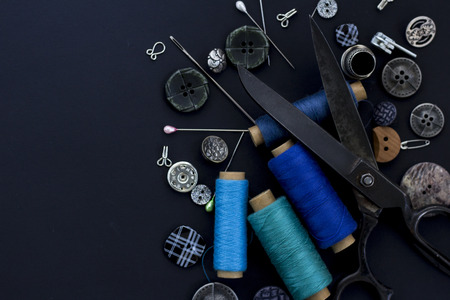 Sewing items,closeup. Scissors,threads, needles and buttons on black background. Top view. Flat lay. Text spaceの写真素材