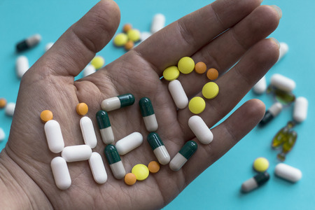 Help sign made of colored pills and capsules in patient hand. Painkiller concept. Drug abuse. Addiction problem.の写真素材