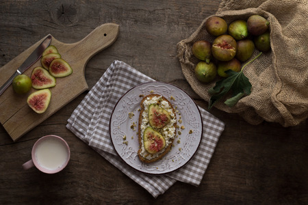 Fresh figs with ricotta garnish with pistachio and pumpkin seeds on a plate. Breakfast table. Healthy eating. Rustic. Flat lay.の写真素材