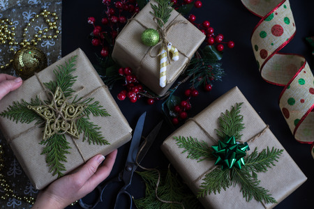 Woman's hands hold Christmas or New Year decorated gift box. Creative, handmade wrapped presents....