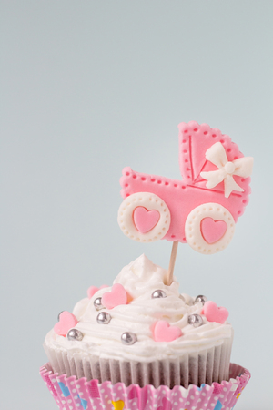 It's a girl cupcake, close up. Newborn background. Baby shower invitation. Baby announcement. Fondant baby accessories.の写真素材