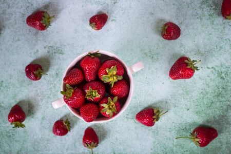 Creative layout made of strawberries in bowl on vintage green background. Organic fresh fruit conceptの写真素材
