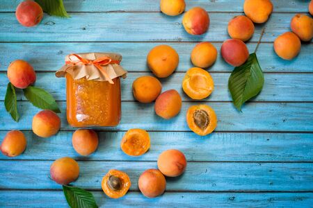 Homemade apricot  jam and fresh organic apricots on blue background. Healthy prepared food.の写真素材