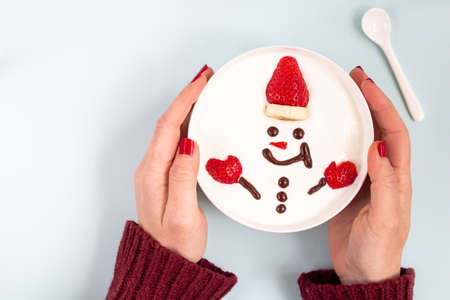 Happy snowman for breakfast. Winter Christmas concept. Woman hands holding bowl with happy  Snowman...