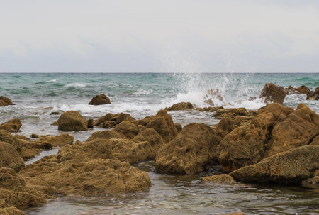 Tropical beach with rocks and waves on the background of cloudy skyの写真素材