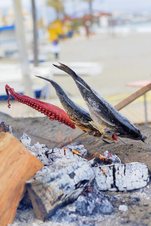 Fish cooking over the coals on the beach at noon.の写真素材