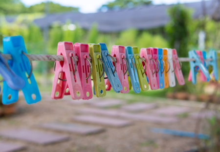 Multicolored beautiful clothespins hanging on a cord, blur backgroundの写真素材