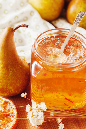Pear and orange jam jars with ripe pears on the table. Close upの写真素材