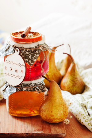 Pear and orange jam jars with handmade label and golden pears on the table. Selective focus.の写真素材