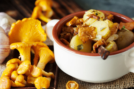 Fried potatoes with chanterelle mushrooms on wooden backgroundの写真素材