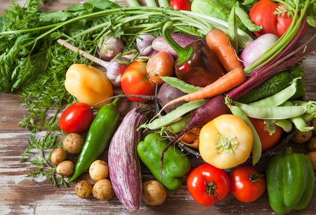 Assortment of raw fresh vegetables in basket from garden on rustic wooden background copy spaceの写真素材