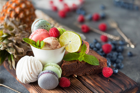 Assorted sweets, macarons, chocolate cake and Marshmallows with mint and fresh berries close upの写真素材