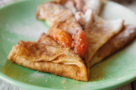 Cinnamon pancakes with caramelized peaches and cane sugar on plateの写真素材