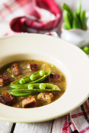 Bean soup in bowl with fresh green pea pods and rye toasts close upの写真素材