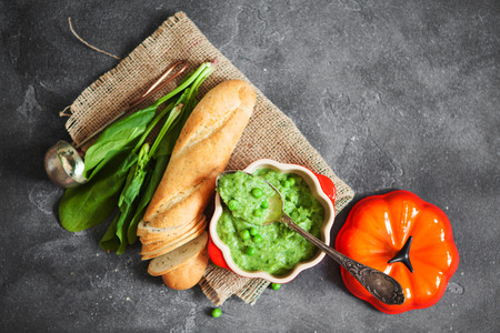 Green cream soup of spinach, pea and broccoli in orange pumpkin bowl. Concept of  healthy food and diet, top viewの写真素材