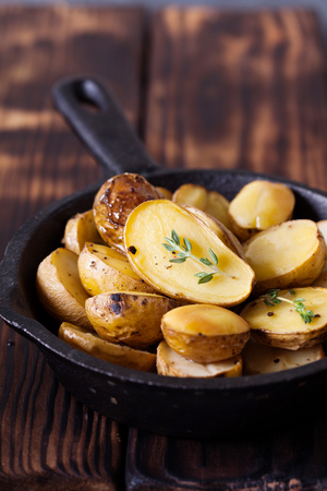 Baked spicy potatoes with thyme on cast-iron frying pan, closeupの写真素材