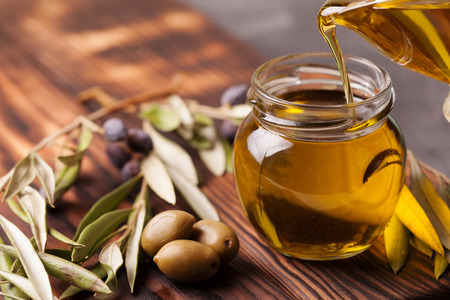 Bottle pouring extra virgin olive oil in a bowl copy spaceの写真素材
