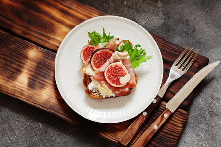 Sandwich with ham, ricotta cheese and figs on white plate top viewの写真素材