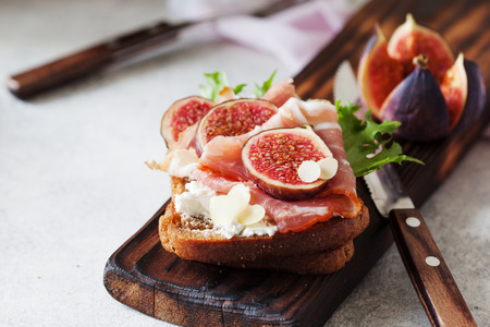 Sandwich with ham, ricotta cheese and figs on white plate close upの写真素材