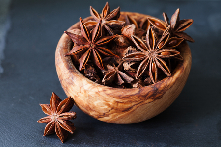 Anise stars closeup in wooden bowl on dark backgroundの写真素材