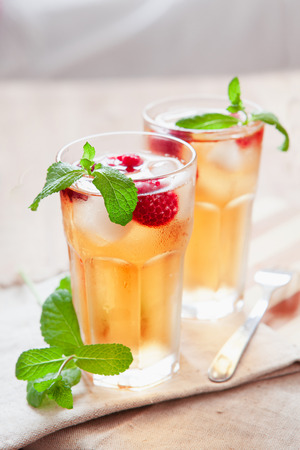 Refreshing summer drink with syrup, raspberry, mint and ice. Glasses with cold and healthy beverage, place for textの写真素材