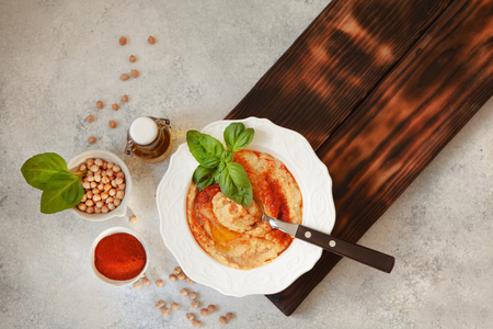Fresh classic hummus with basil in the bowl on white background, top viewの写真素材