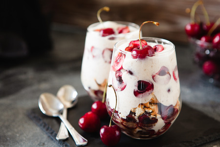 Homemade trifle pudding with freshcherry on dark background, portion of sweet cheesecake in Ð° glass, selective focus copy spaceの写真素材