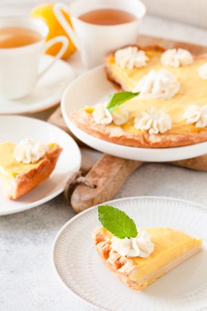 Piece of traditional shortcrust pastry lemon tart with citrus custard and decorated with whipped creamの写真素材