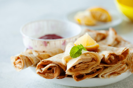 Lemon crepes on the plate with strawberry sauce