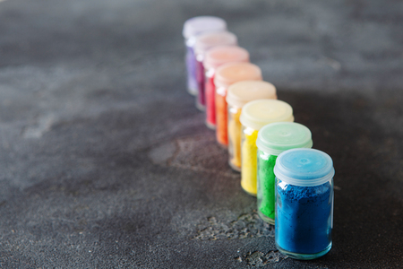 Bright colourful powdered pigments in glass bottles for Indian holi festival on dark slate background, copy space. Colorful gulal for Happy Holiの写真素材