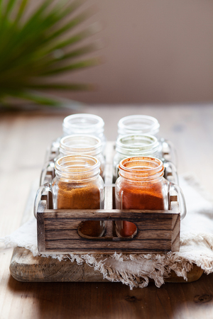 Spices and seasonings in glass jars on wooden containerの写真素材
