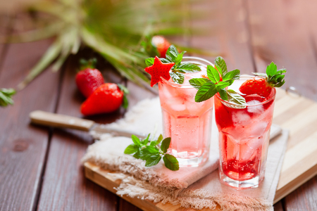 Sparkling summer pink lemonade with fresh strawberry on dark wooden background, copy spaceの写真素材